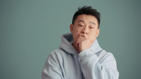 Bored Asian man wearing hoodie looking at the camera