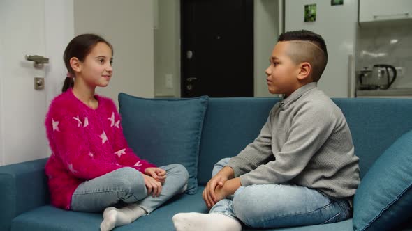 Multiethnic Kids Playing Gesturing High Five Sitting on Sofa Indoors