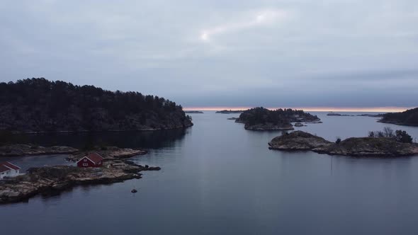 Evening aerial - Flying above ocean surface in Lillesand Norway towards horizon and North sea - Clou
