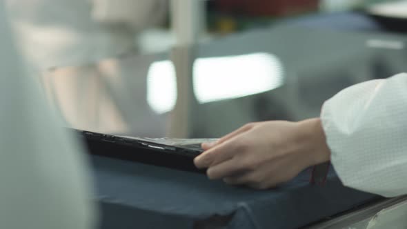 worker installs and checks lcd matrix for tv on factory assembly line