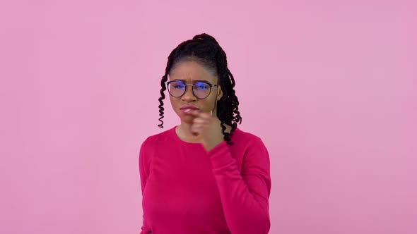A Cute AfricanAmerican Girl in Pink Clothes Looks Thoughtfully and Seriously at the Camera