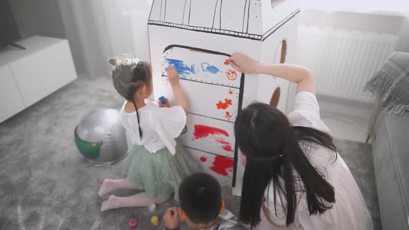 An Asian Female with Kids Play in the Living Room at Home a Boy in an Astronaut Costume Sitting on