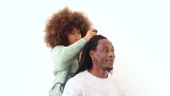 Amazed girl making hairdo on dreadlocks of father