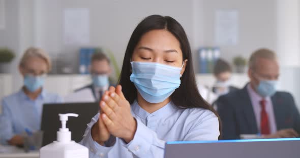 Asian Woman in Safety Mask Cleaning Hands with Antibacterial Gel at Office
