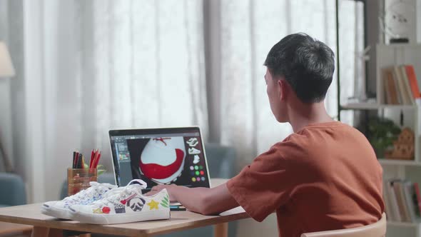 Asian Boy Footwear Designer Thinking While Designing Shoe On A Laptop At Home