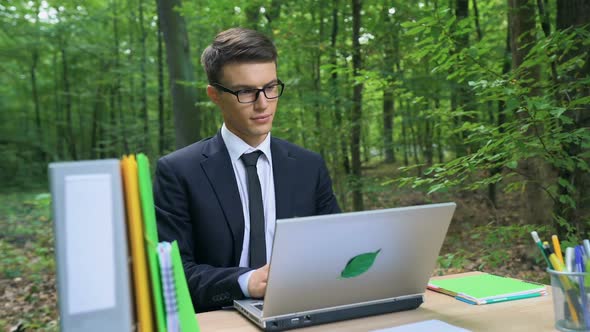 Happy Young Businessman Finishing His Work and Relaxing in Chair in Green Forest