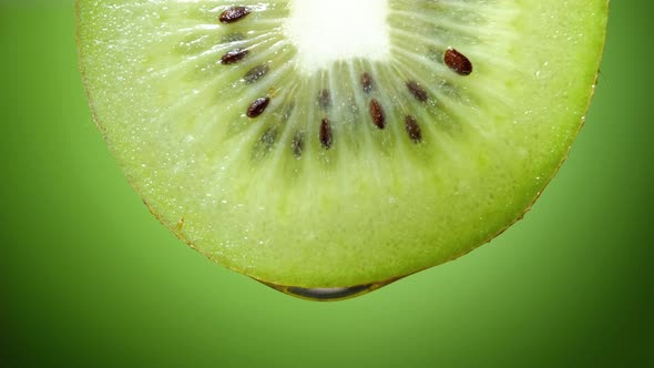 Close Up or Macro of a Slice of Kiwi, a Drop of Water Falls in Slow Motion