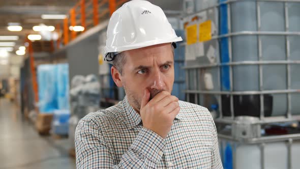 Portrait of Mid-adult Man in Helmet Coughing Feeling Unwell Standing in Warehouse