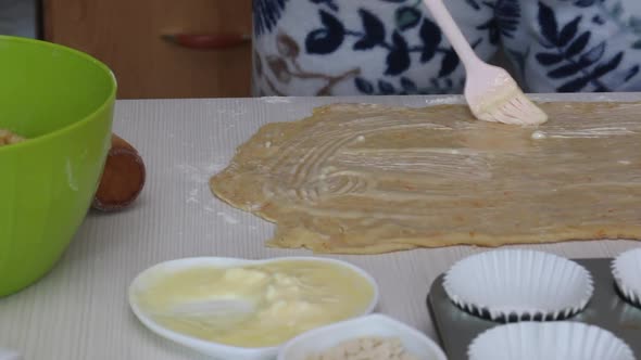 A Woman Butters A Rolled Out Dough. Prepares Cruffin With Raisins And Candied Fruit