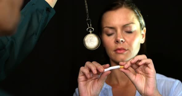Woman breaking a cigarette in front of a pendulum to stop smoke