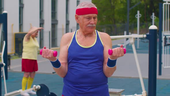 Senior Man Grandfather Doing Training Weightlifting Exercising with Dumbbells on Playground in Park