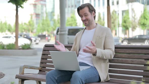 Young Man Talking on Video Call While Sitting on Bench