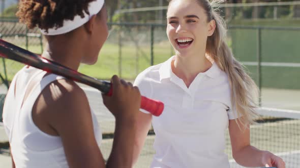 Video of happy diverse female tennis players holding rackets and talking