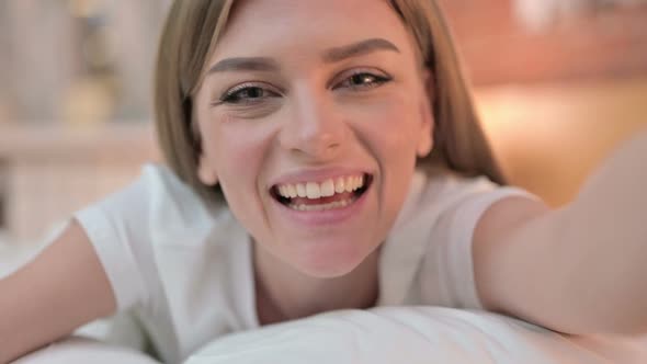 Close Up of Cheerful Young Woman Doing Video Chat in Bed