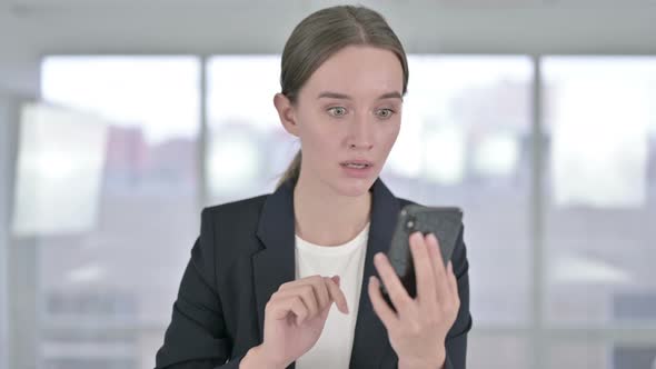 Portrait of Young Businesswoman Reacting To Loss on Smartphone