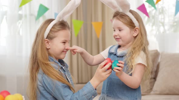 Little Girls with Rabbit Ears Play with Easter Eggs in Game of Who Will Break