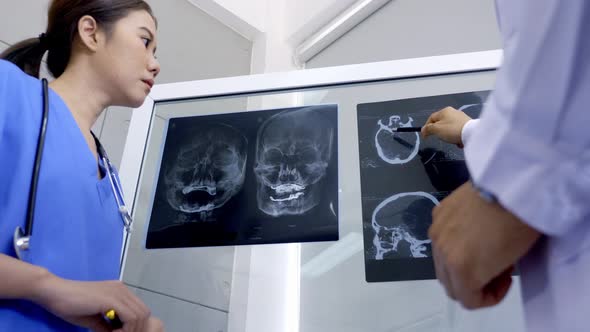 Doctor and medical assistants discussing about diagnosis result on x-ray film. alt