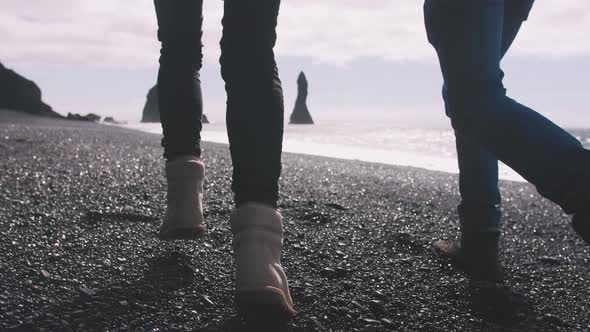 Close Up Shot of Young Couple Holding Hands Running Down Black Sand Beach in Iceland Slow Motion
