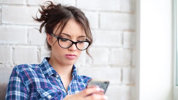 Casual Young Woman Using Mobile Phone at Home in a Daylight