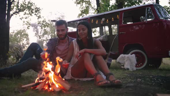 Beautiful Young Mixed Race Couple Roasting Marshmallows Over a Campfire While Enjoying Their Road