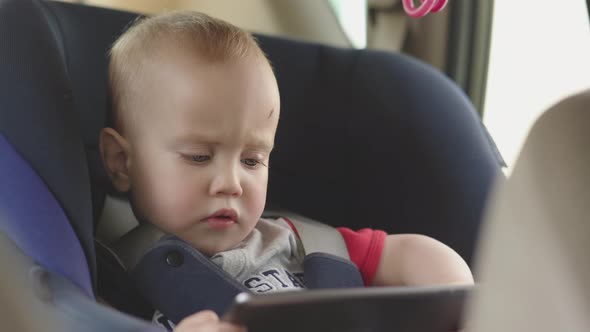 Little Baby Toddler Child Kid Sitting in Carseat Using Digital Tablet Watching