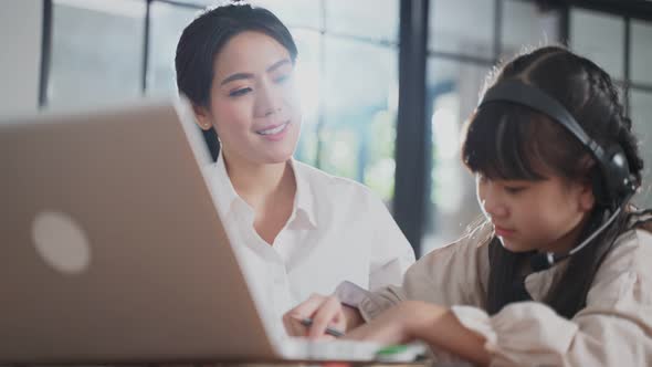 Asian family learning from home together. Young girl kid studying education class with mother.