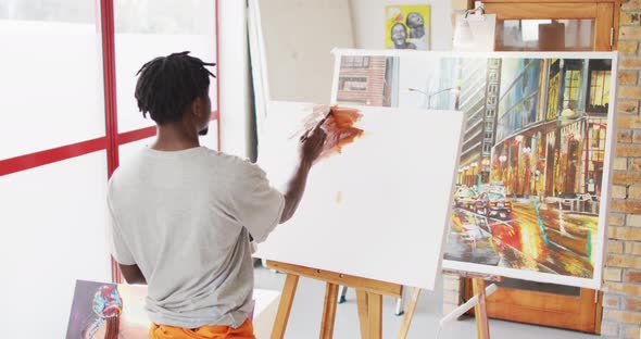 African american male painter painting on canvas in artist studio