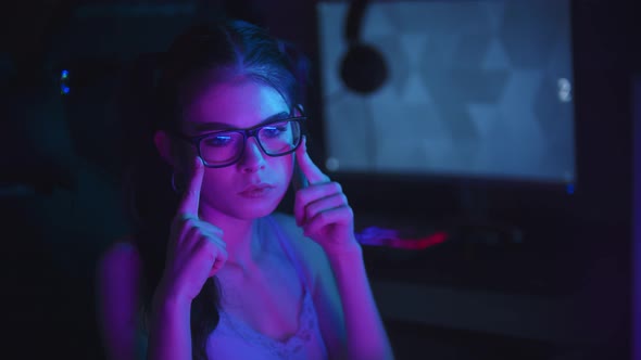 Young Attractive Woman Resettling Her Spectacles in Neon Club