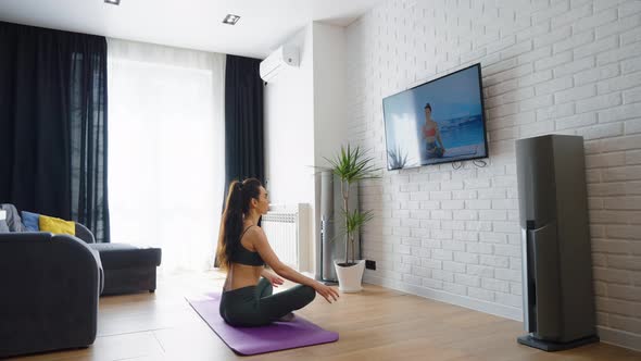 Woman Watching Online Yoga Class and Meditating at Home