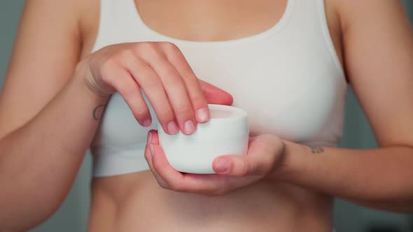 The Girl Opens a Jar of Cream and Takes the Cream with Her Finger