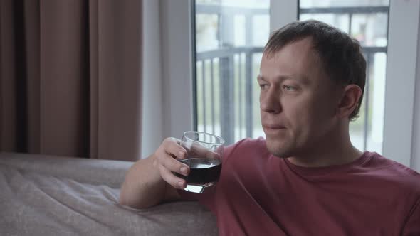 Man Relaxing at Home Sitting on Sofa and Drinking From a Glass Relaxation Concept