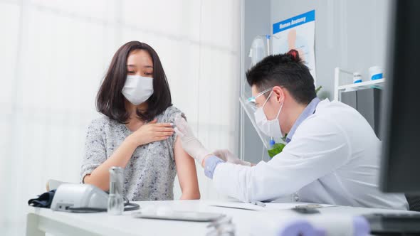 Asian male doctor wear mask, give treatment to young woman in hospital.