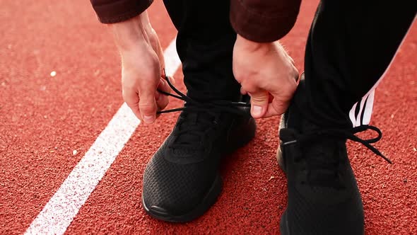 Man Tying his Running Shoes on te Stadium