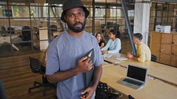 Tracking Shot Portrait of Young African American Employee Posing with Papers at Workplace