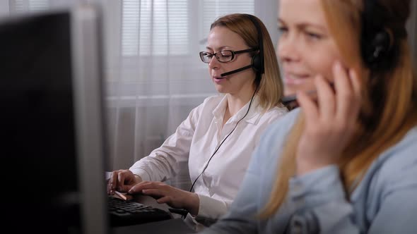 Two Female Call Center Operators with Headset Work in a Support Service Office