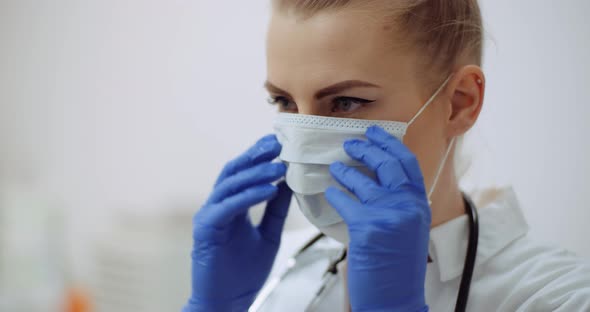 Female Doctor Putting on Protective Mask at Clinic