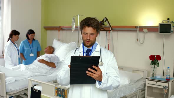 Doctor reading report while nurse interacting with patient in background