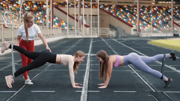 Sportswomen and Coach Doing Squats with Resistance Fitness Rubber Band on Stadium