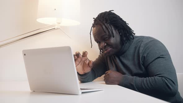 Young African American Man Using Laptop and Showing Gift to His Wife on Video Call