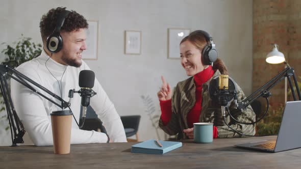 Male and Female Podcast Hosts Speaking in Mics in Recording Studio