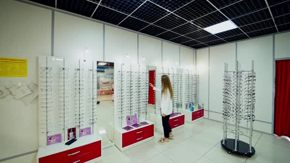 Woman at optical shop. Woman choosing her new glasses at optics store