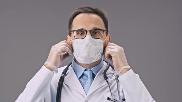 Handsome Lab Technician in Medical Uniform Takes Off Protective Mask and Smiles