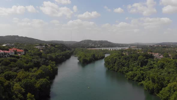 High drone shot of redbud isle with hill country and neighborhood clearly visible.