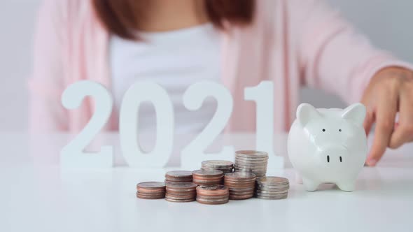 Stack of coins with young woman putting coin into the piggy bank