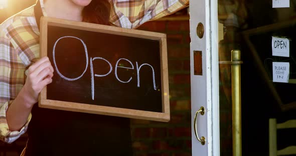 Waitress showing chalkboard with open sign