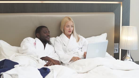The Couple Spent the Night at the Hotel, the Wife Works Behind a Laptop While Her Husband Just Wakes