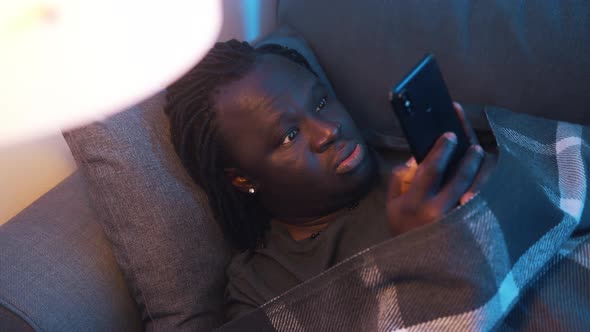 Depressed African American Black Man Reading Email Wrapped in Blanket