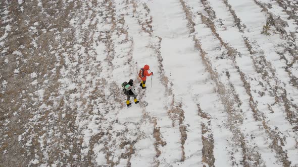 Aerial View of Two Male Hikers Walking in Untouched Snow Mountain Landscape. Aventures Journey Trip