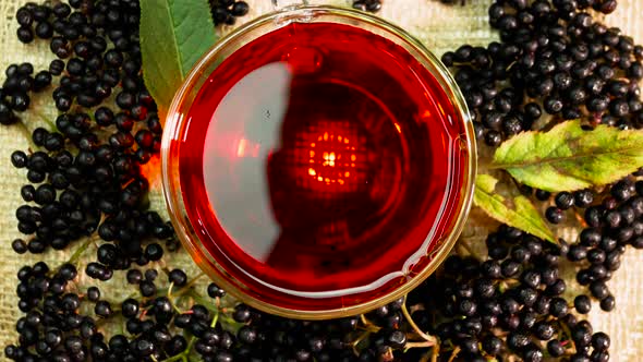 Slow Motion Natural Red Berry Tea In A Glass Cup On An Old Bag With A Berry Branch. Berry Tea