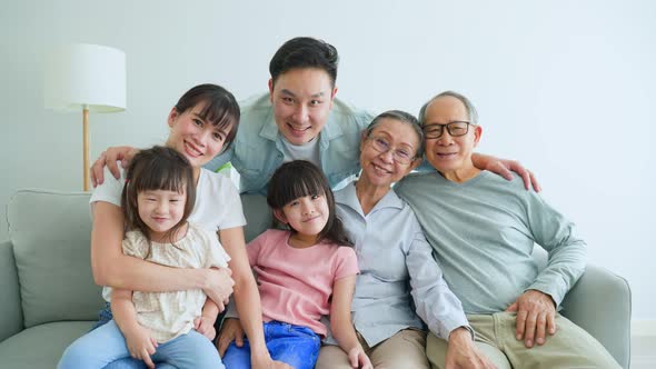 Portrait of Asian big family feel happy to spend time together and look at camera in living room.